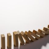 Unas fichas de madera cayendo una tras otra para representar las consecuencias y sanciones de no cumplir con Verifactu
